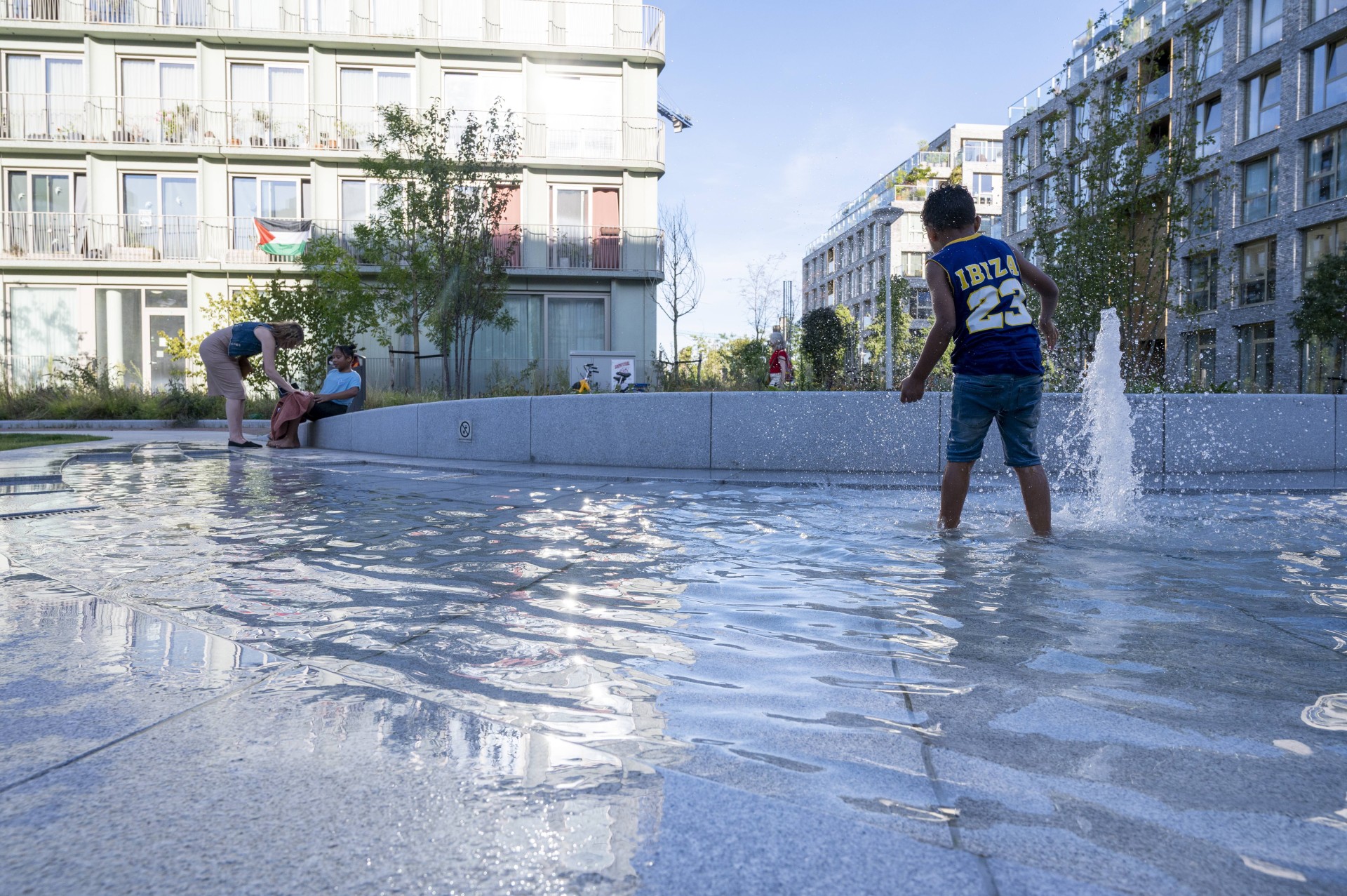 Jongen speelt in het water van de fontein op het Buurtplein in Overhoeks