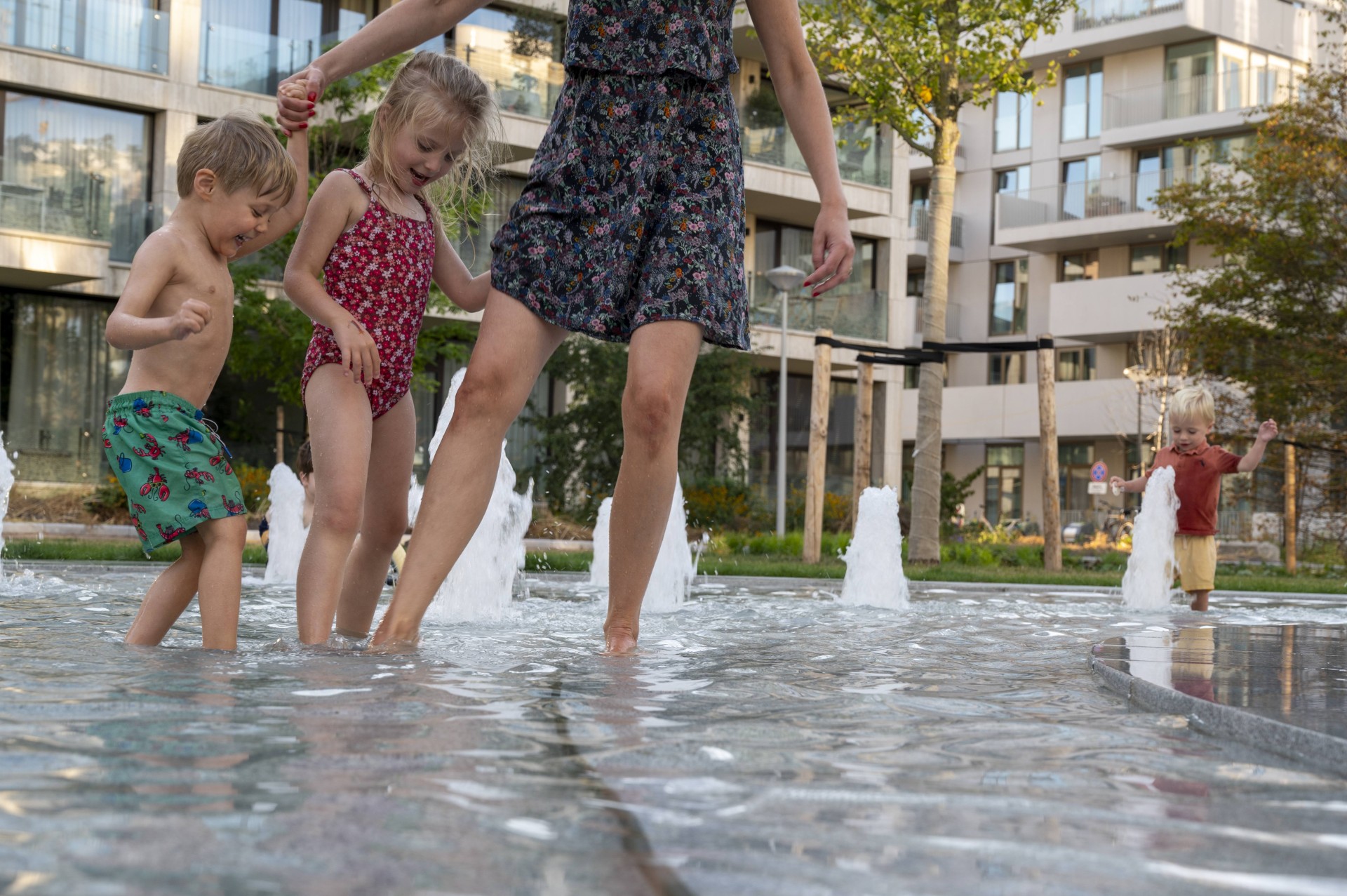 Kinderen en een ouder lopen door het water van de fontein op het Buurtplein
