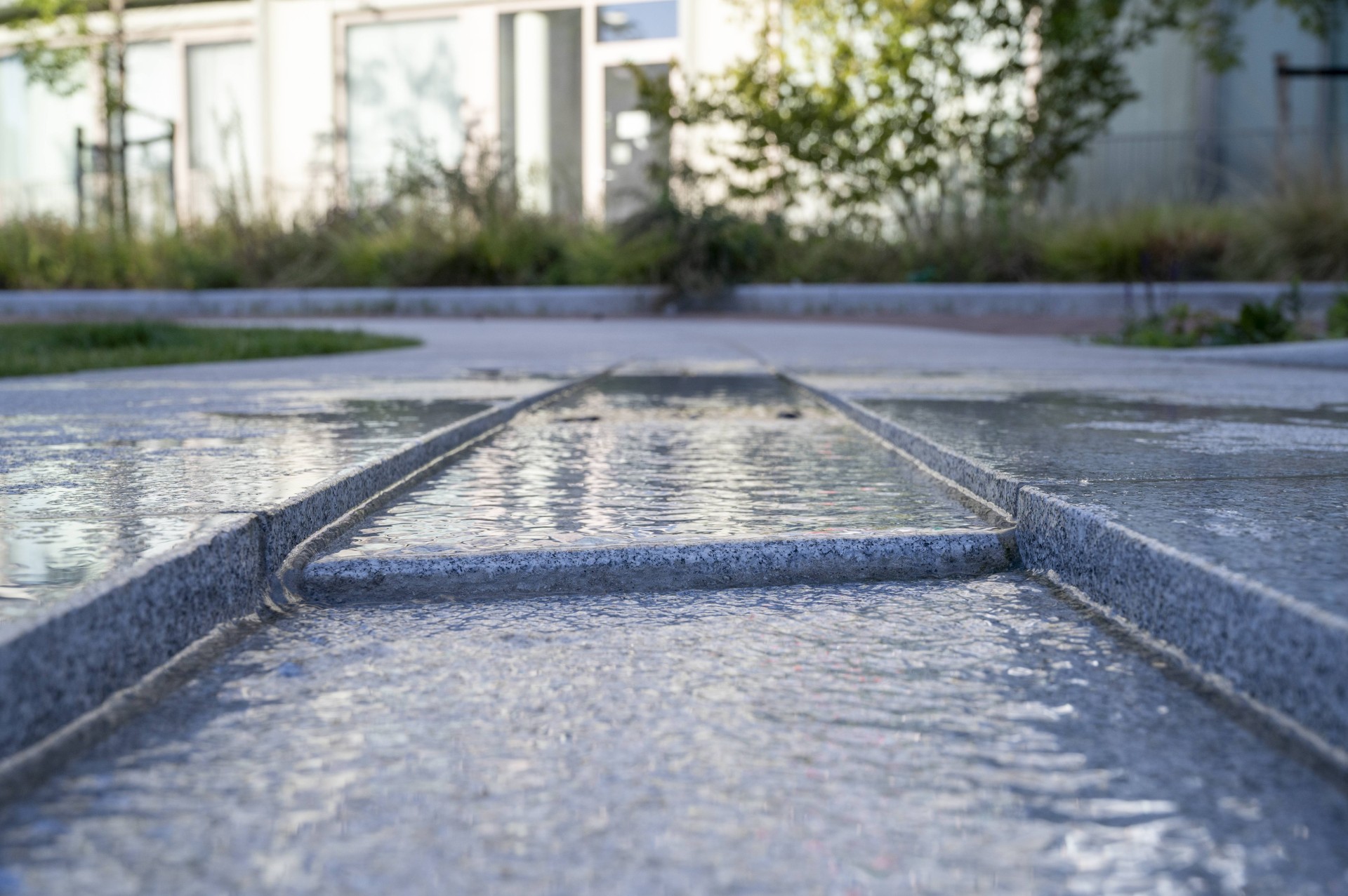 De natuurstenen lijn met een waterlaag bij de overgang naar het gras op het Buurtplein