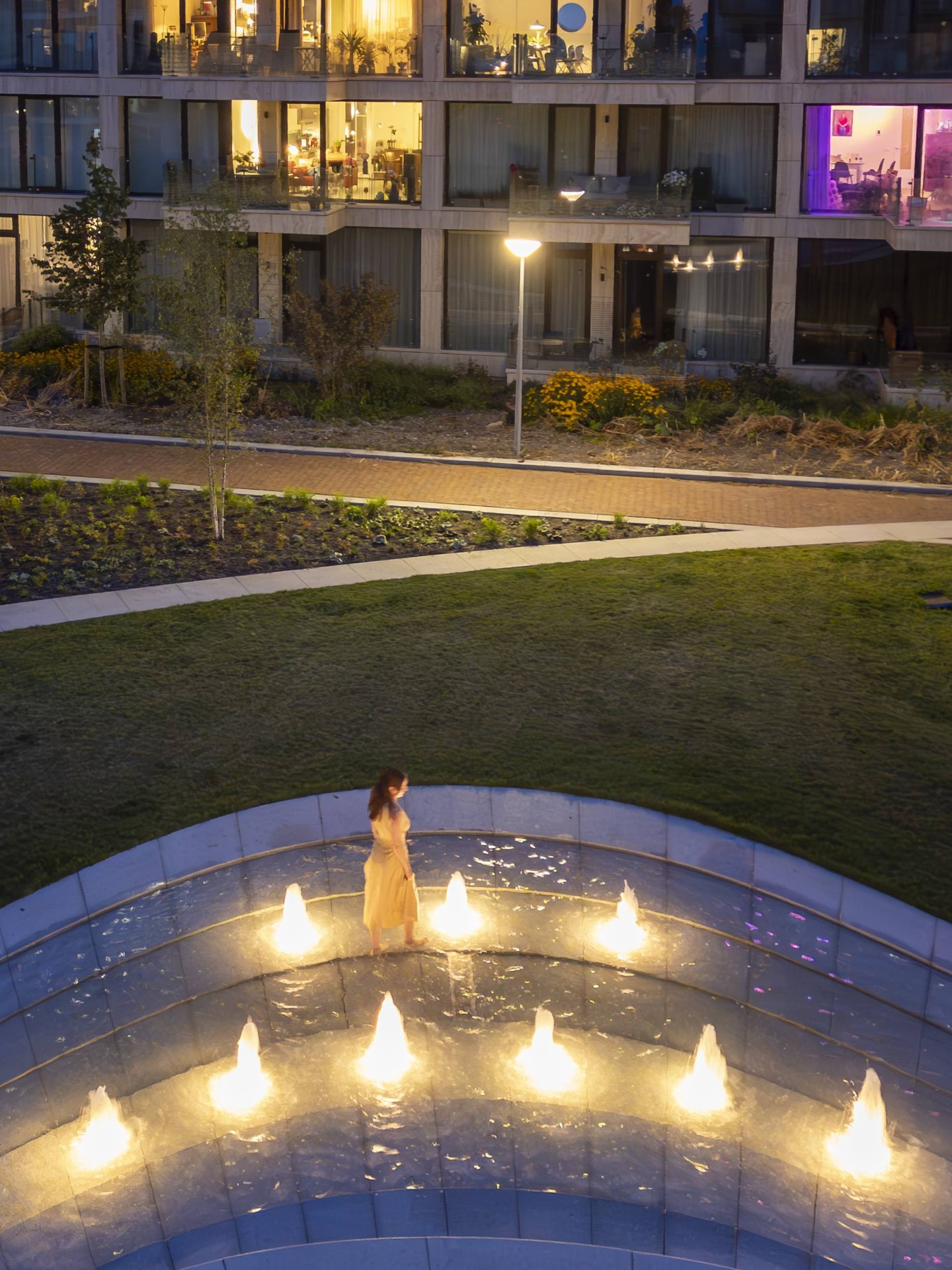 De verlichte fontein op het Buurtplein in Overhoeks in de avond
