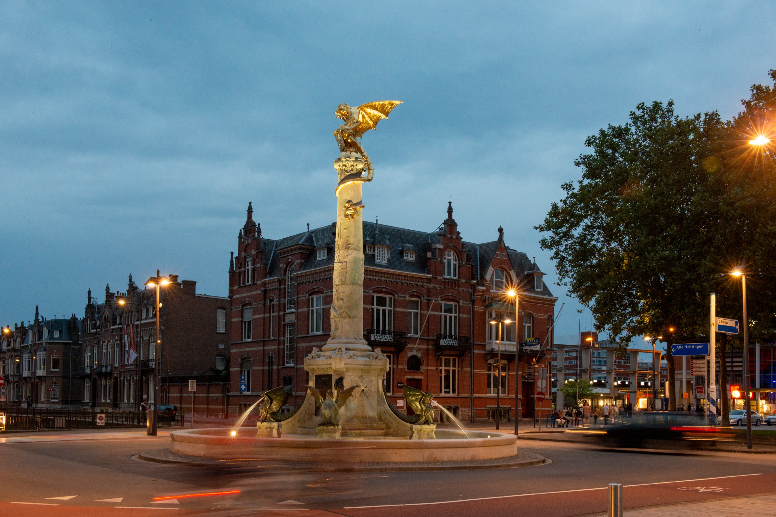 De Drakenfontein in Den Bosch met de gouden draak, verlicht in de schemering