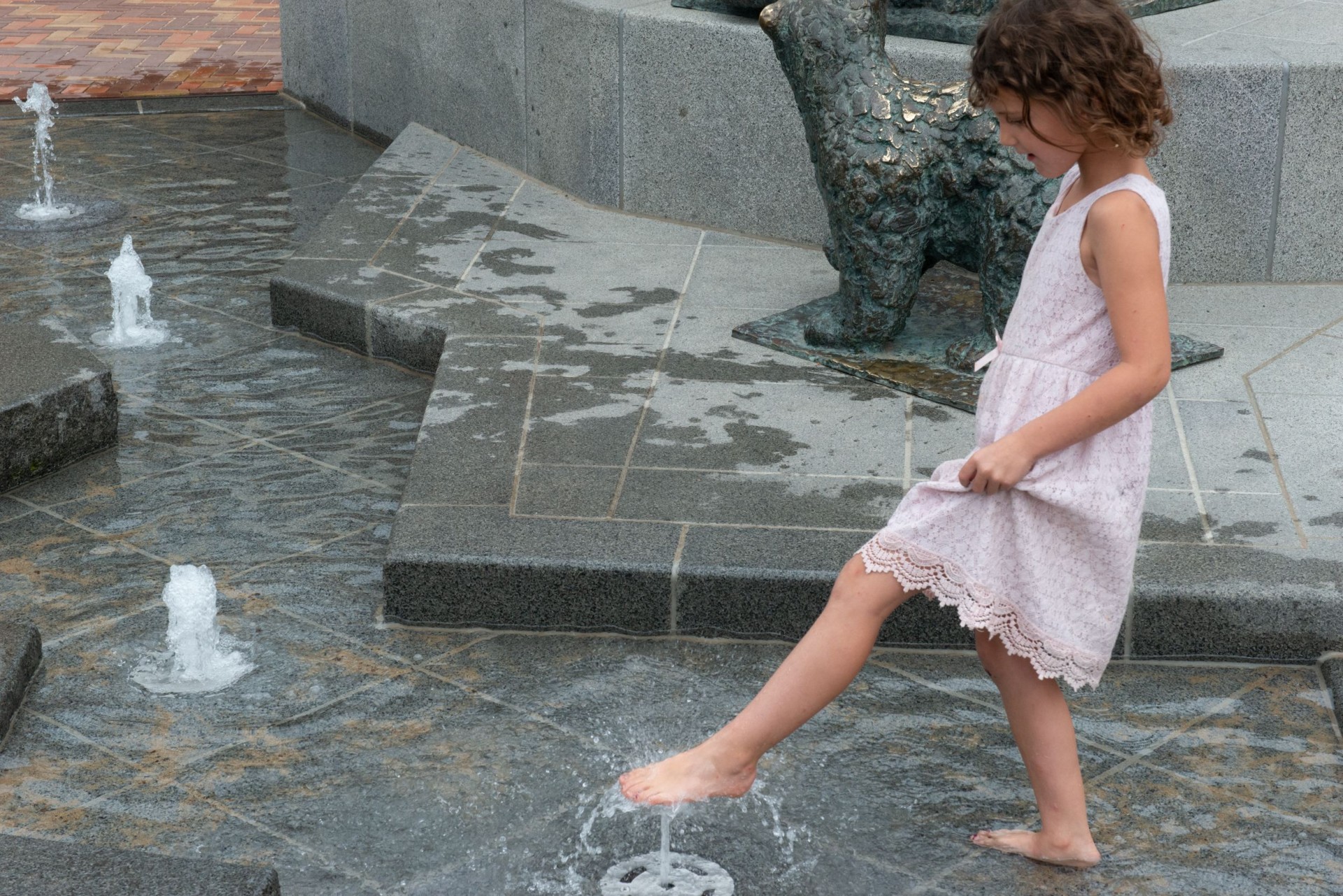 Meisje speelt in het water tussen de natuurstenen ijsschotsen en fonteintjes in Dieren