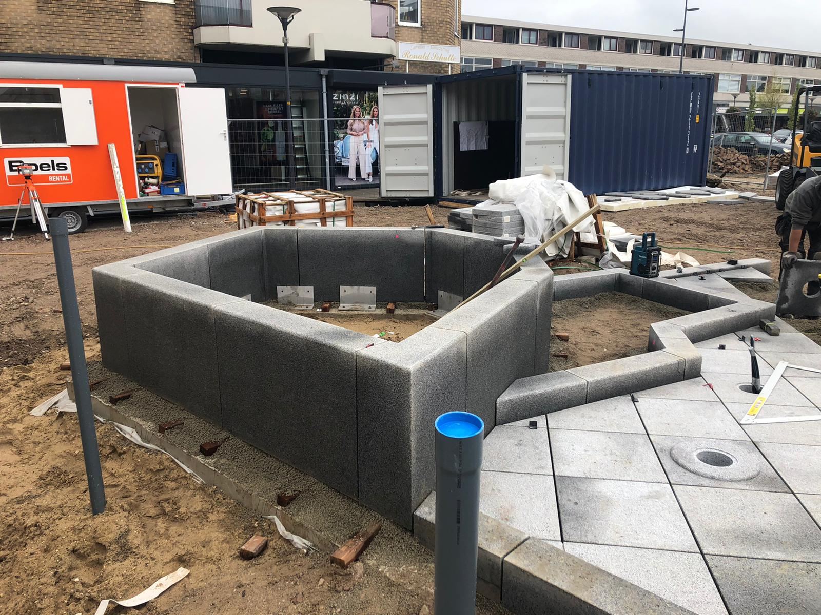 Werkers plaatsen de natuurstenen randen van de ijsschotsen voor de ijsberenfontein in Dieren