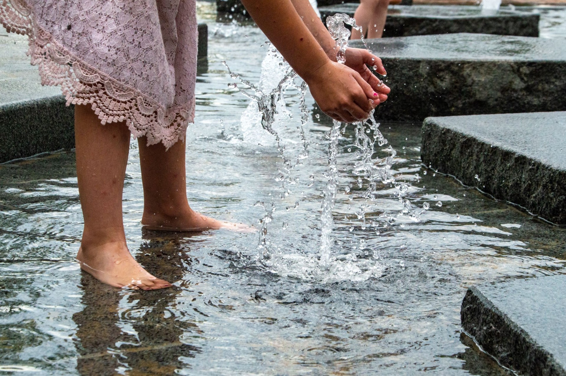 Meisje speelt met het water van de fonteintjes tussen de natuurstenen ijsschotsen in Dieren