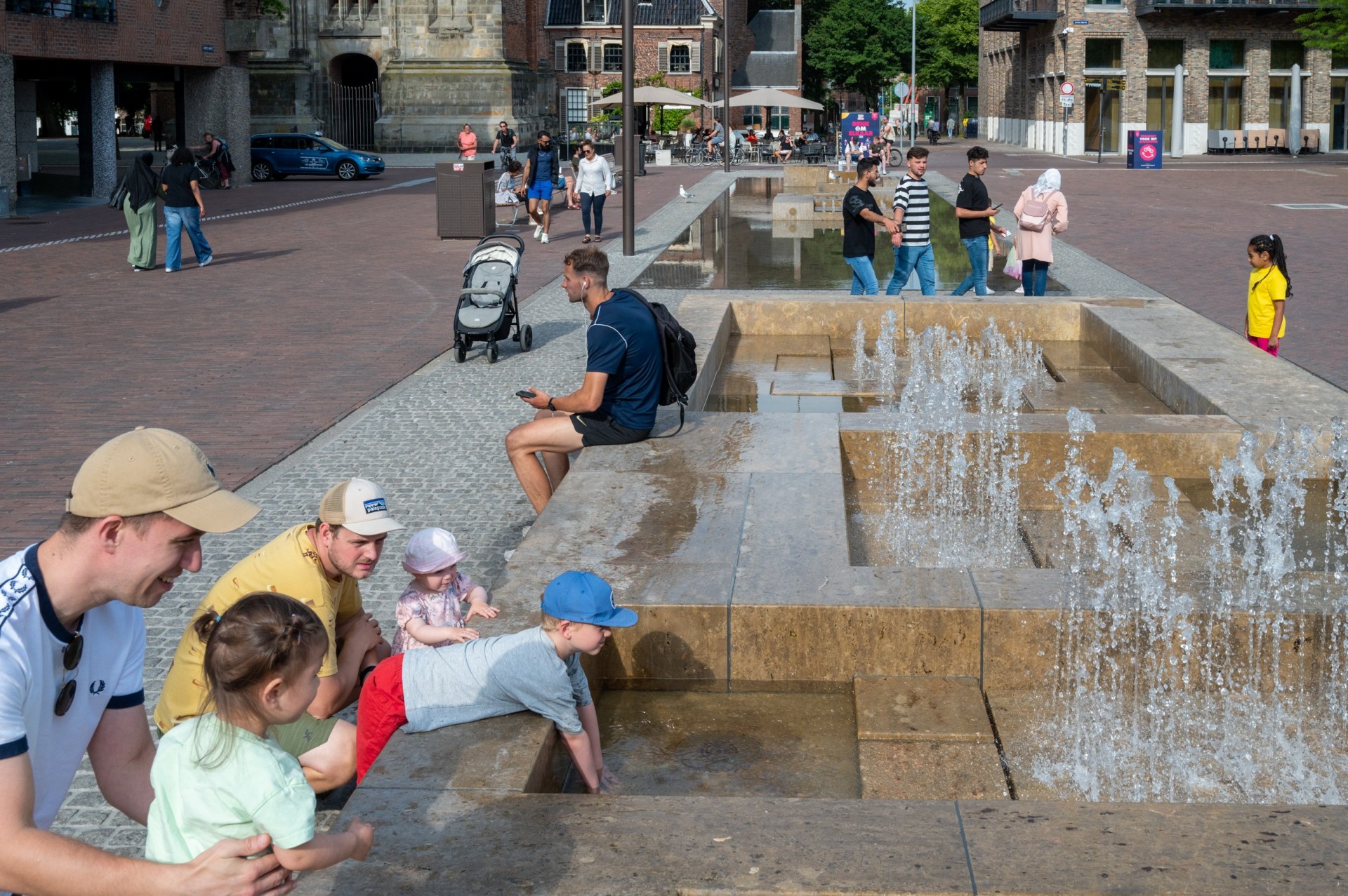 Grote Markt Groningen: ouders en kinderen spelen bij een waterelement van natuursteen