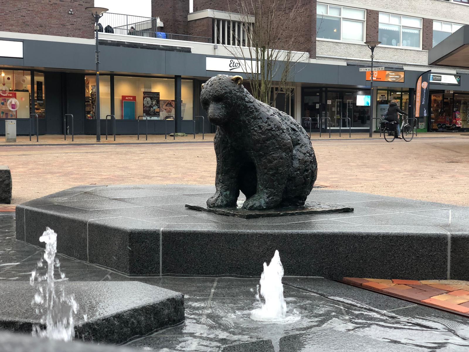 Bronzen ijsbeer op de natuurstenen sokkel met waterstralen op het Callunaplein in Dieren