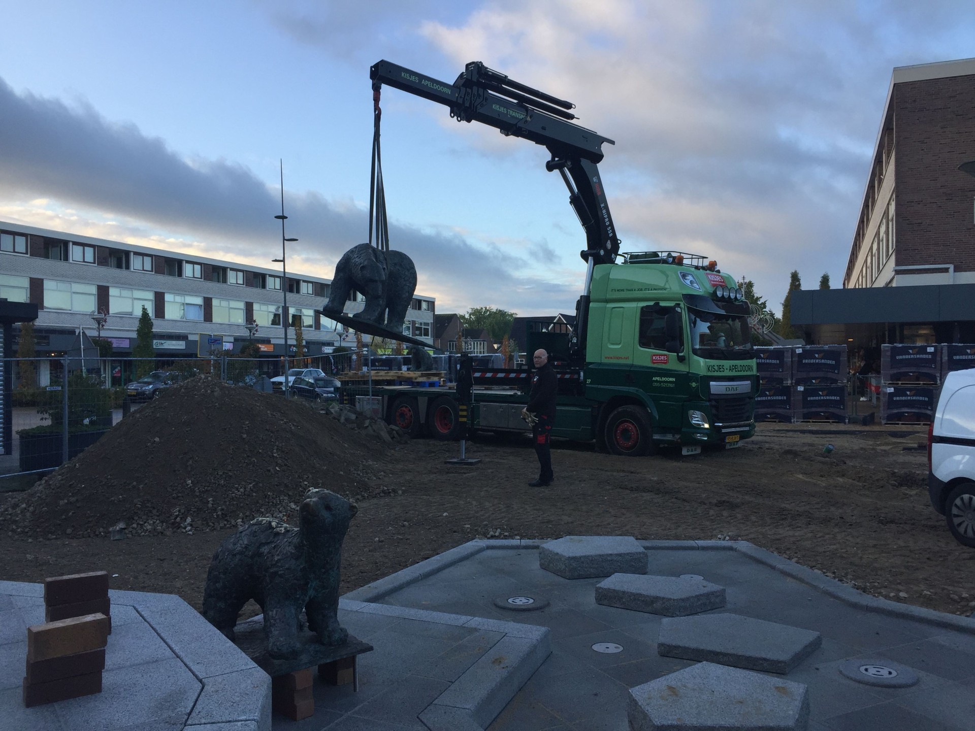 Een bronzen ijsbeer hangt aan de kraan bij het terugplaatsen op het Callunaplein in Dieren in de avond