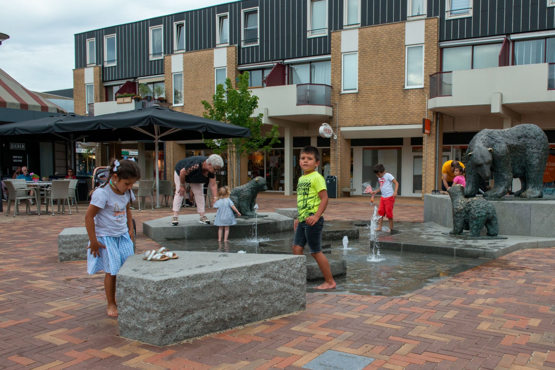 Kinderen spelen op de ijsschotsen tussen de bronzen ijsberen van de fontein in Dieren