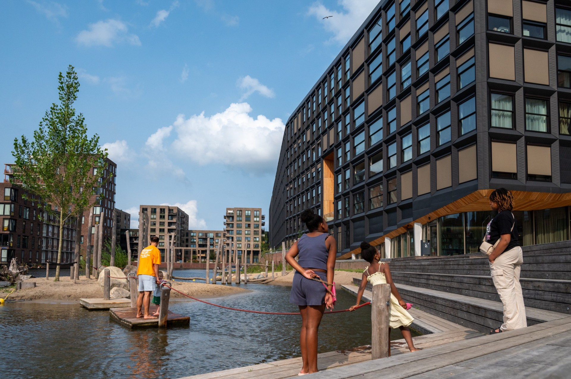 Kinderen spelen op een drijvend platform in de haven voor het woongebouw Jonas