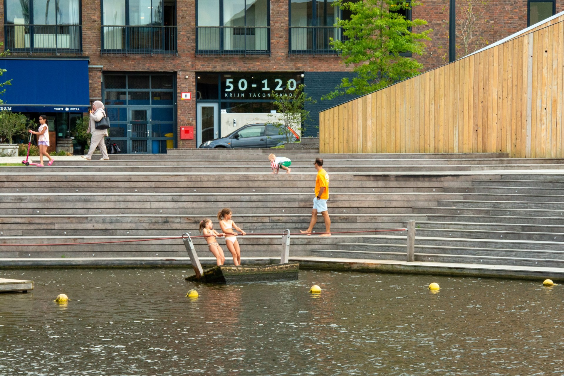 Kinderen spelen op de trappen bij het water voor de houten tribune van Jonas