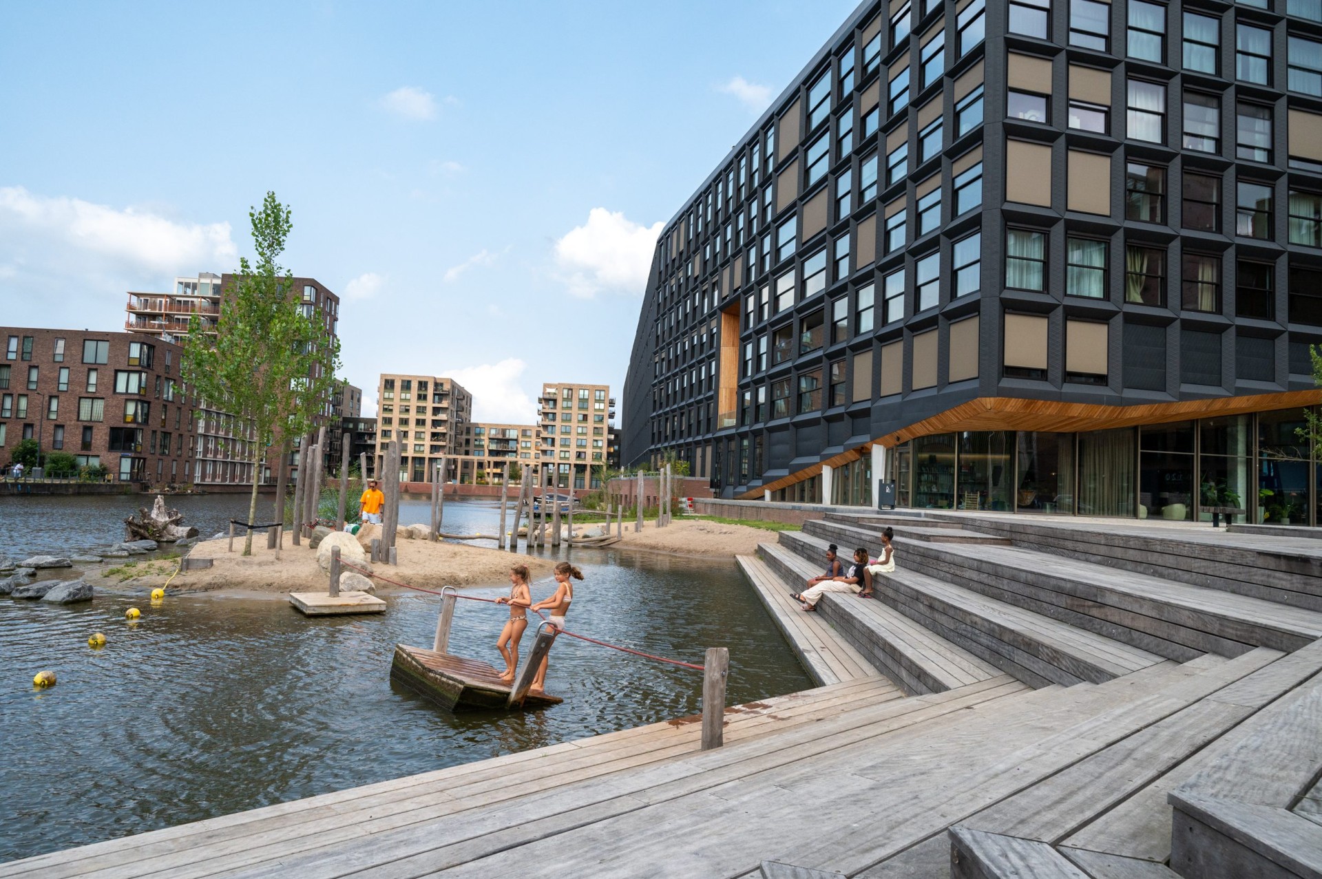Kinderen spelen aan het water bij de houten trap en het dek van Jonas