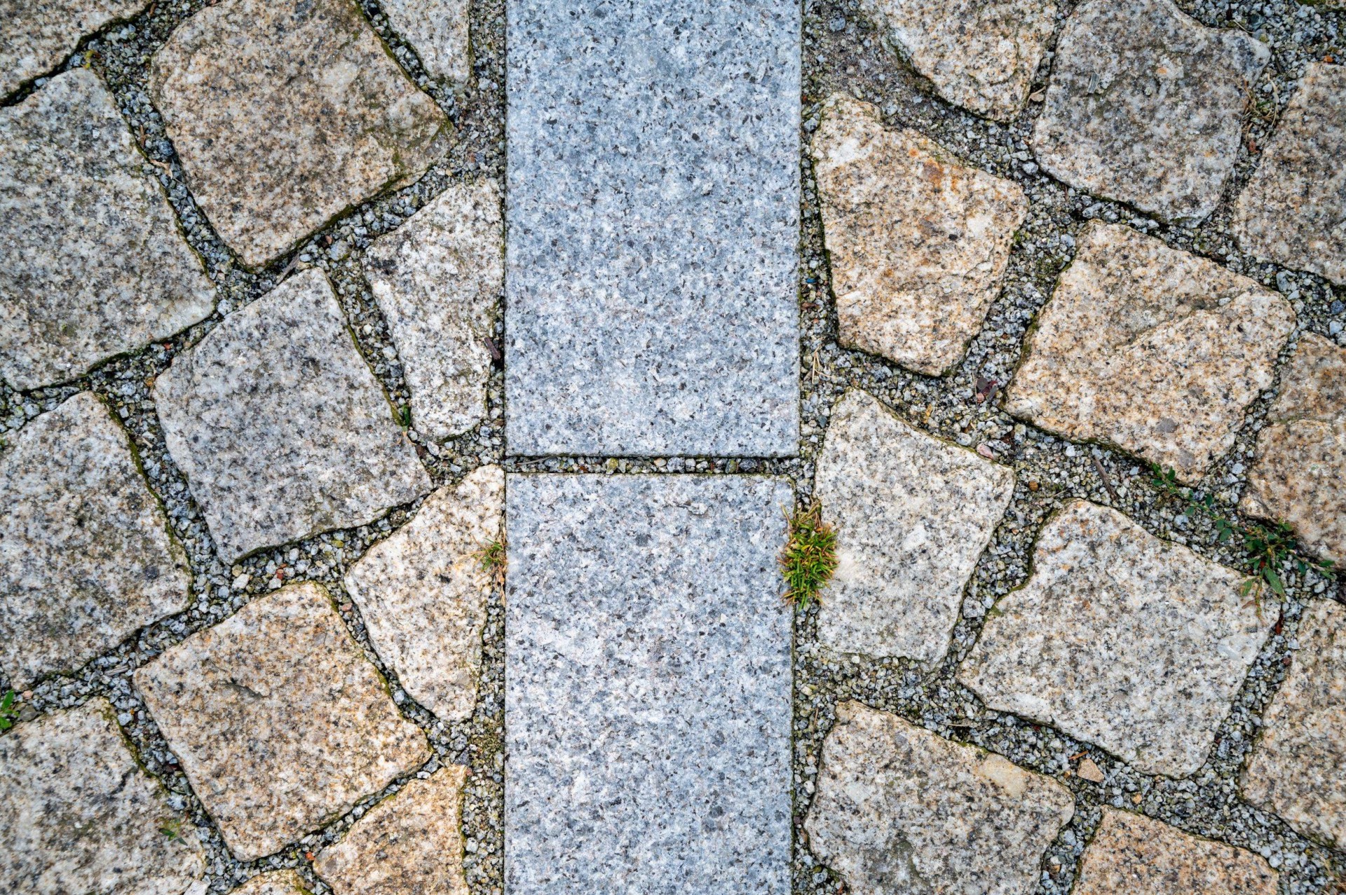 Detail van natuursteen: Portugese graniet keitjes met een strook gezaagd graniet op het dak van Jonas