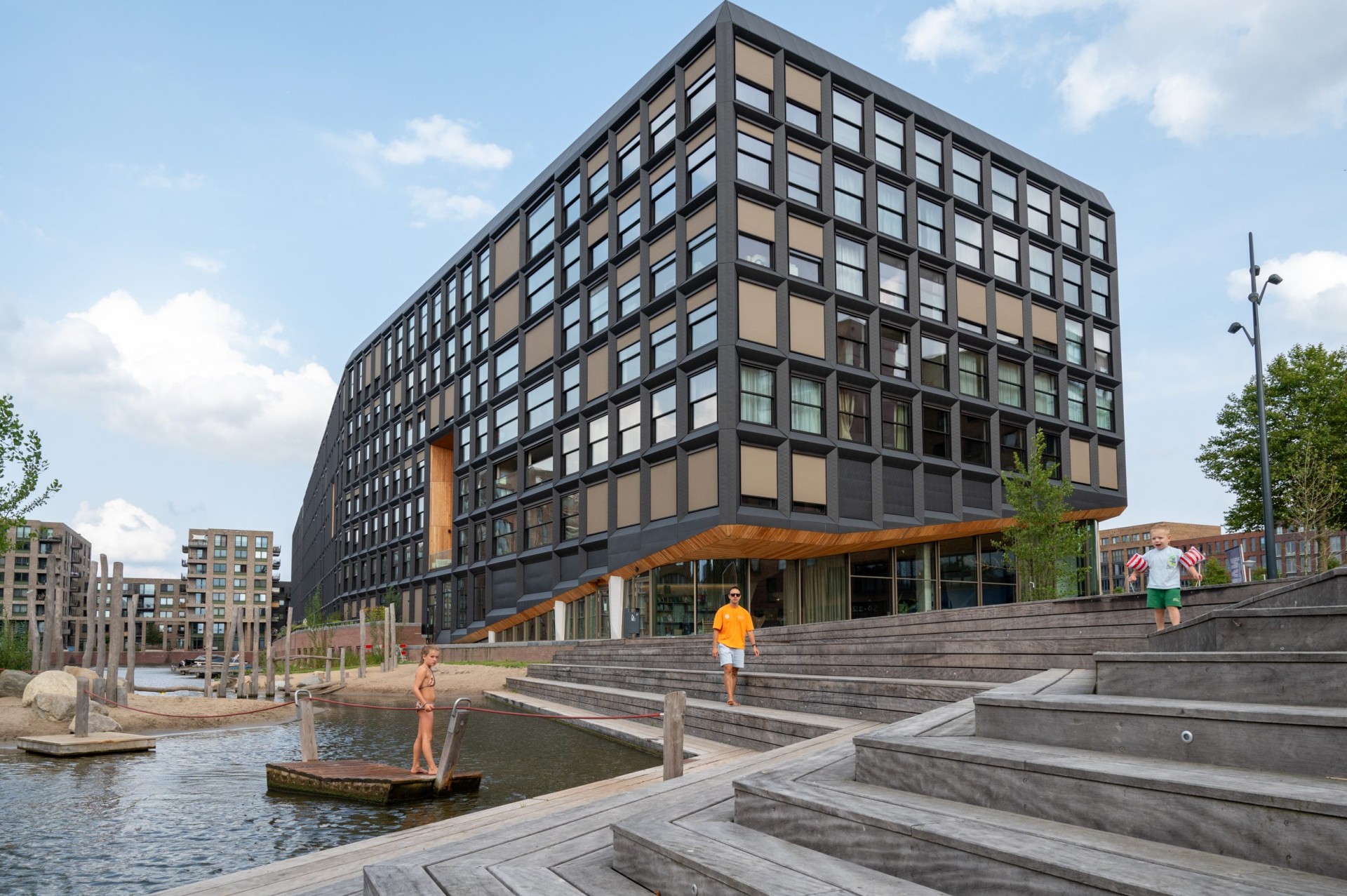 Het woongebouw Jonas met zwarte gevel, trappen en kinderen aan het water