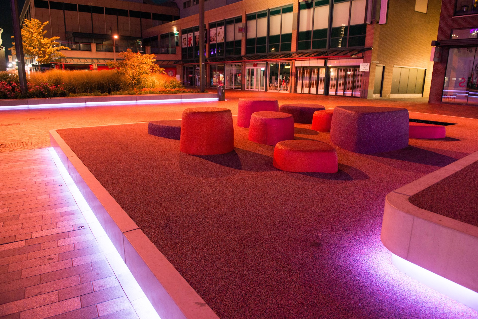 LED-lichtlijn langs een betonband met oranje speelelementen op de Nieuwe Markt in Roosendaal in de avond
