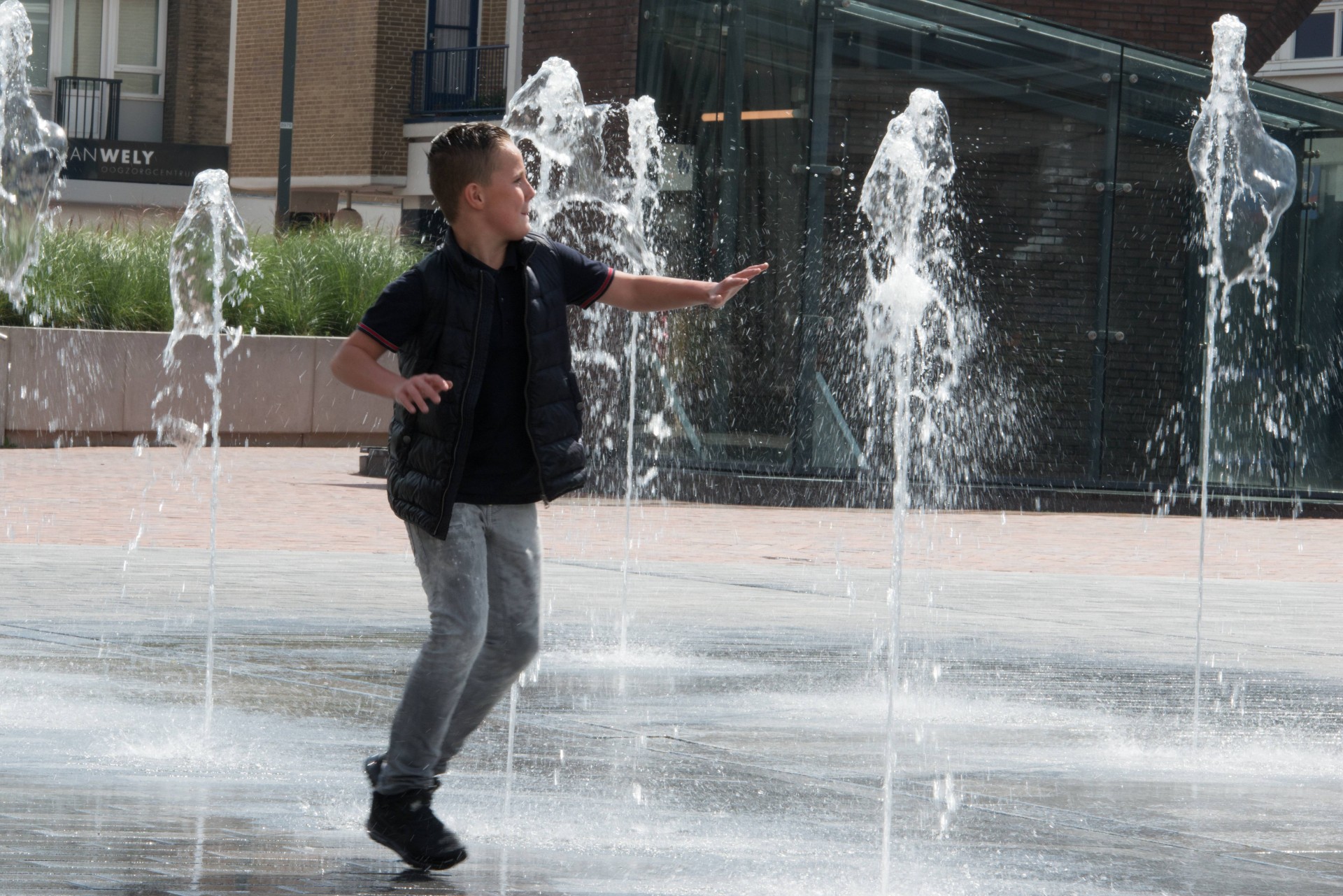 Jongen speelt in de fonteinen op de Nieuwe Markt in Roosendaal