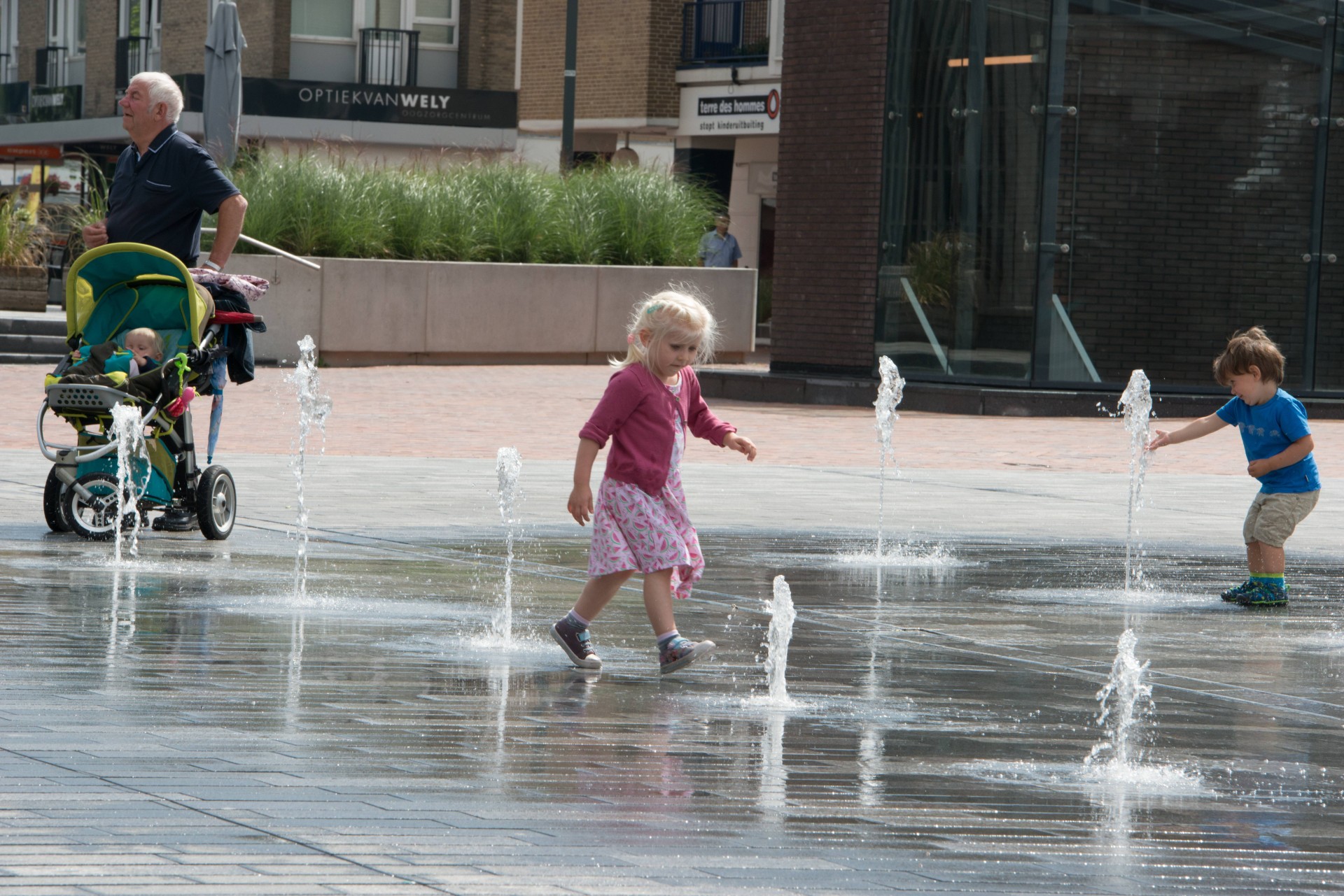Kinderen en een kinderwagen bij de fonteinen op de Nieuwe Markt in Roosendaal
