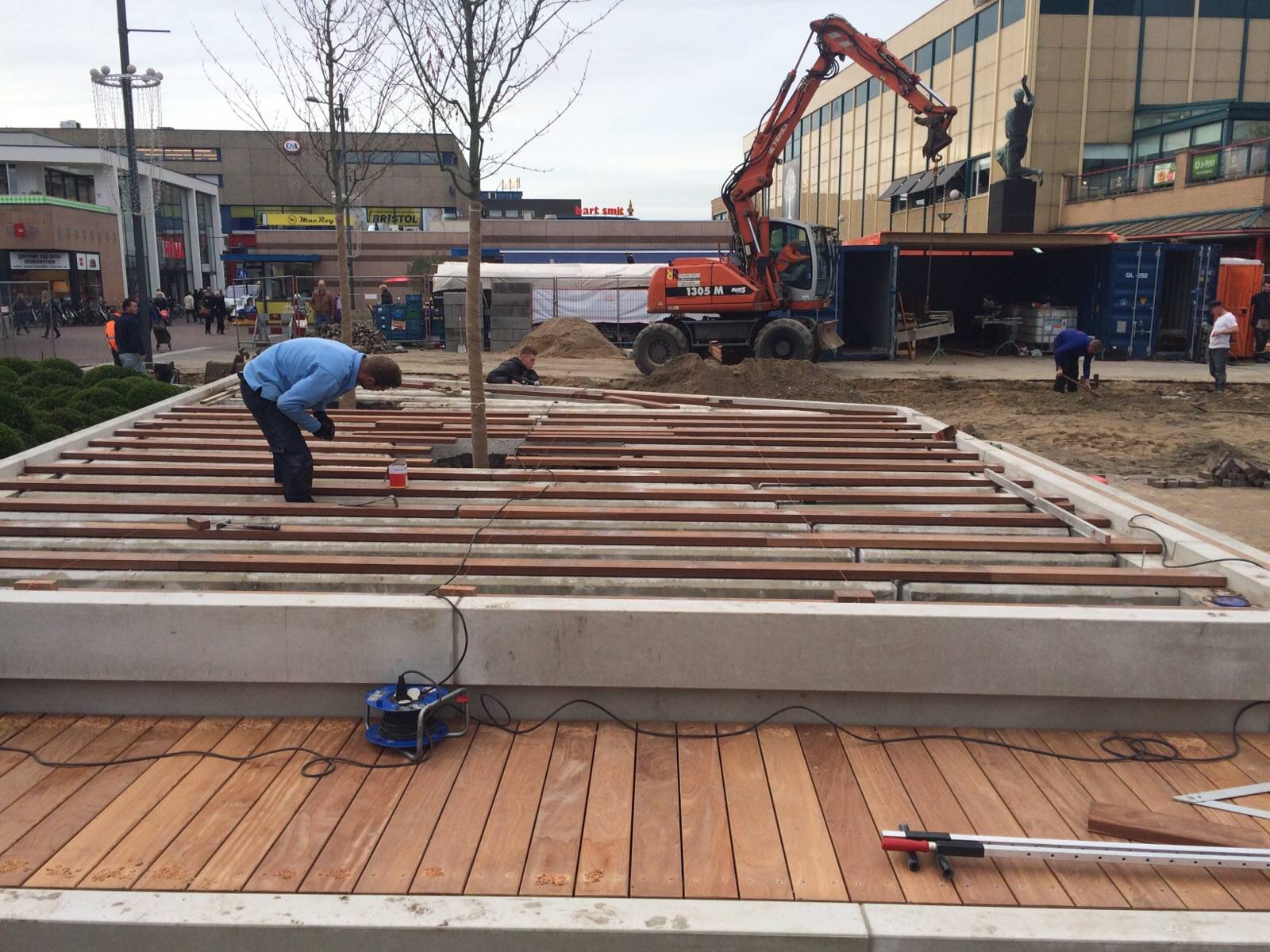 Monteur legt hardhouten vlonders op een betonband op de Nieuwe Markt in Roosendaal