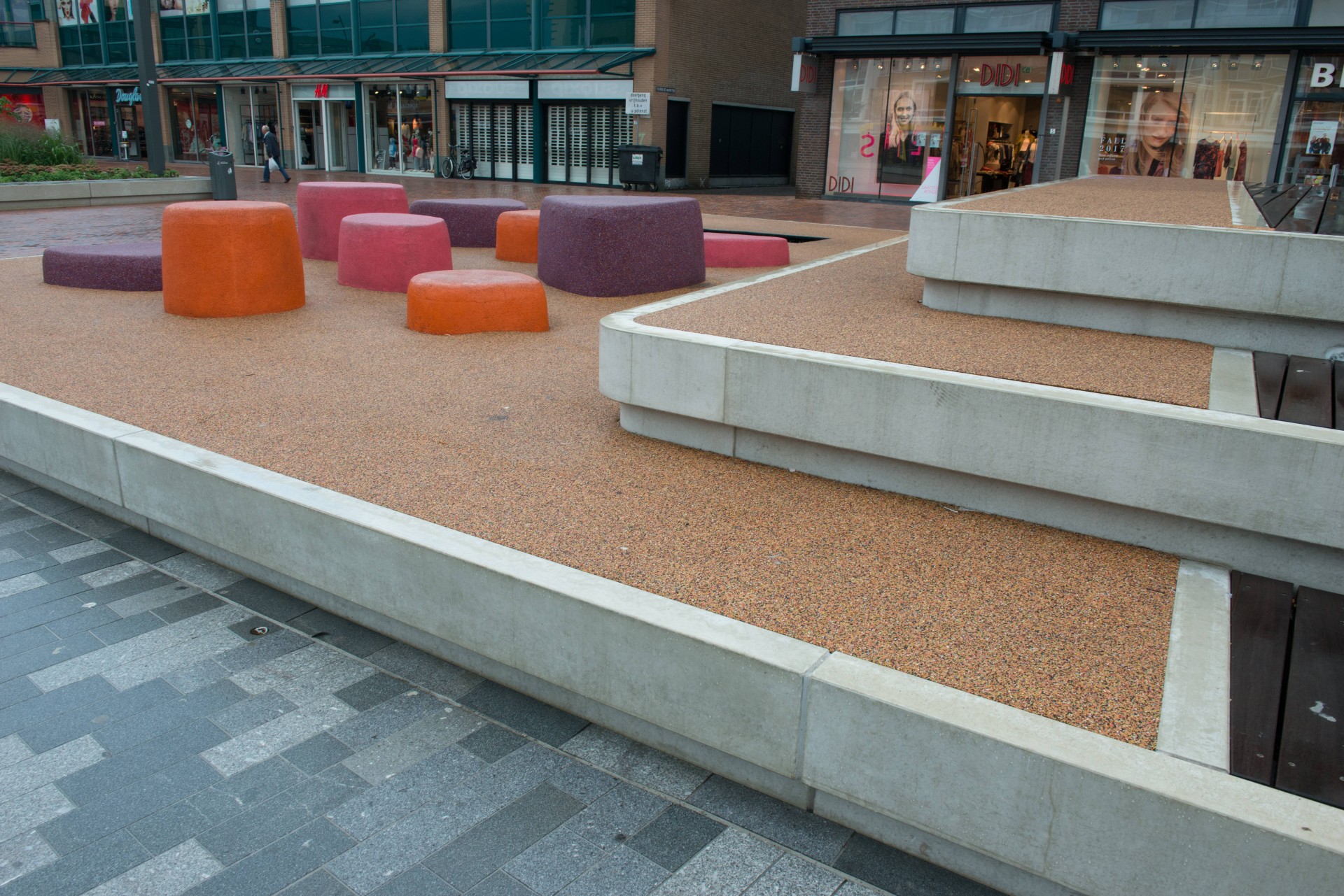 Speelelementen naast een betonnen zitrand en de speelvloer op de Nieuwe Markt in Roosendaal